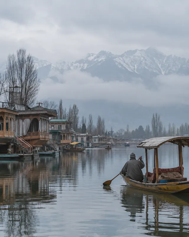 A boatman paddling a shikara past houseboats on Dal Lake, Srinagar